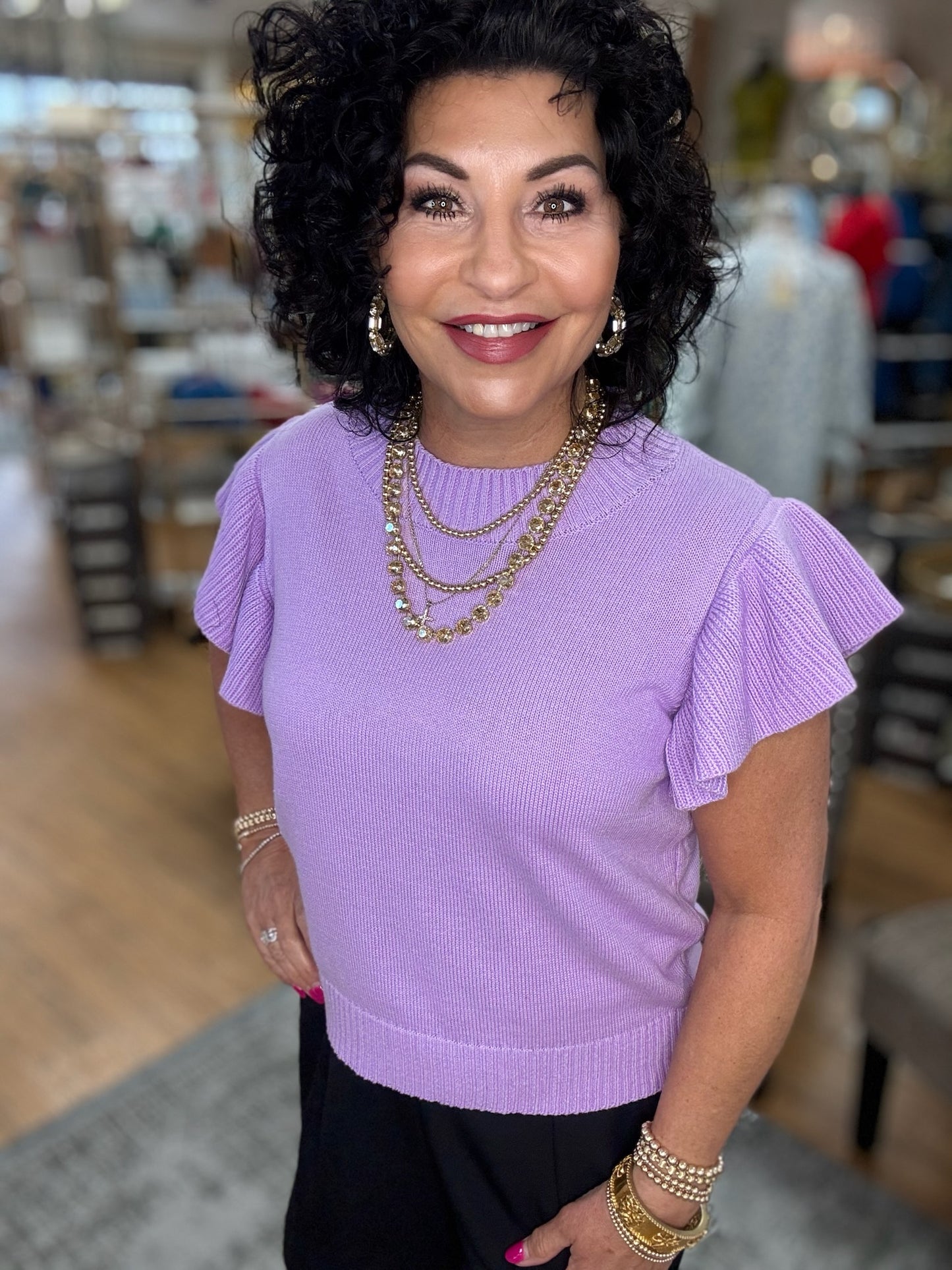 Solid knit top with a crew neck (adjustable stretch), ruffled shoulder, and ribbed hemline.