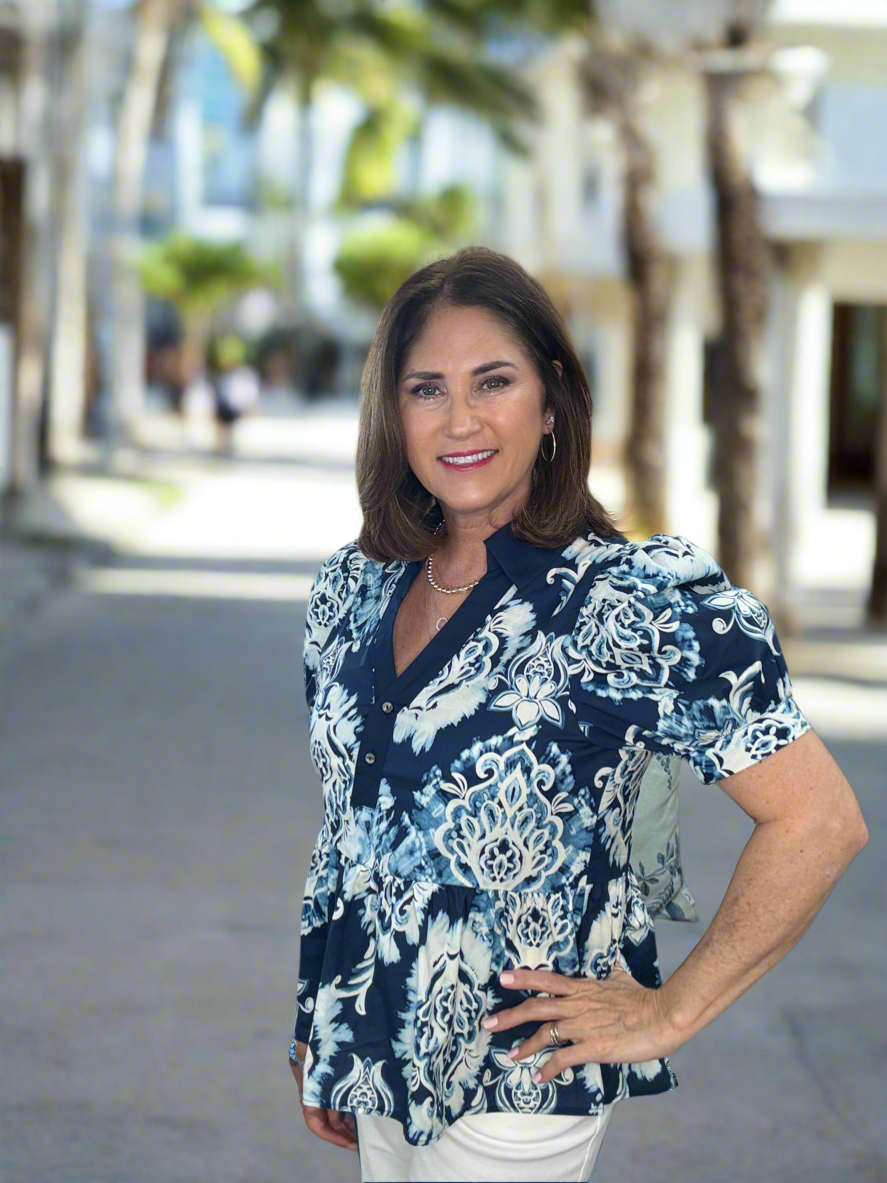 Boho-inspired print cuff band short puff sleeve pullover ruffle hem top featuring contrast accented spread collar button front closure