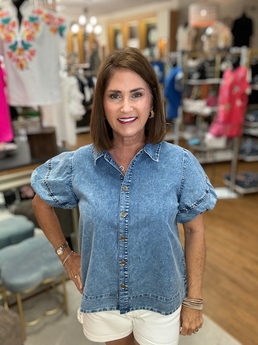 Denim top with collared neck, short puffed sleeves, and vented hemline.