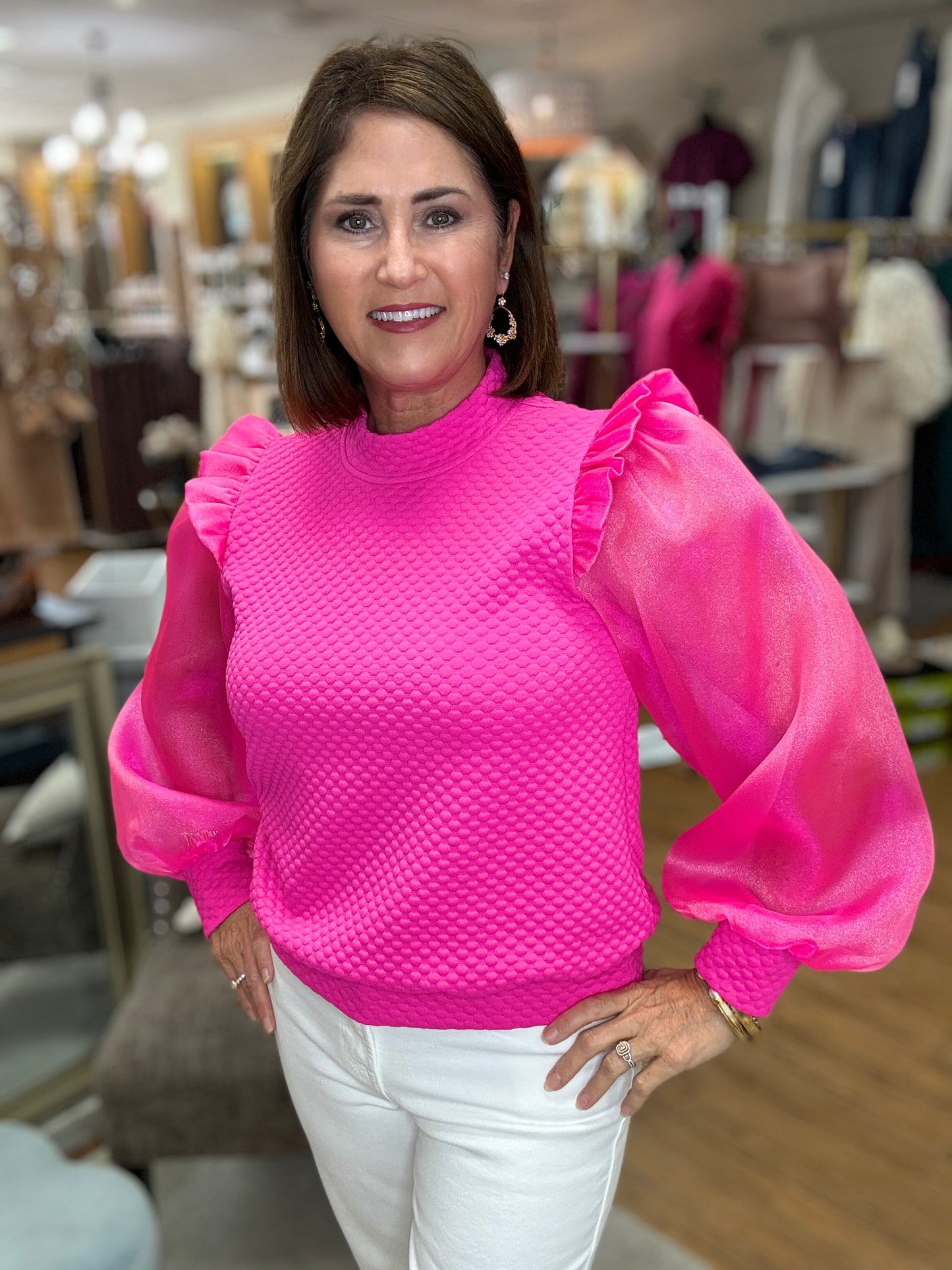 Mixed textured fabric feminine top with mock neck, back buttoned closure, frilled shoulders, long puffed sleeves, and ribbing at the sleeve ends and hemline.