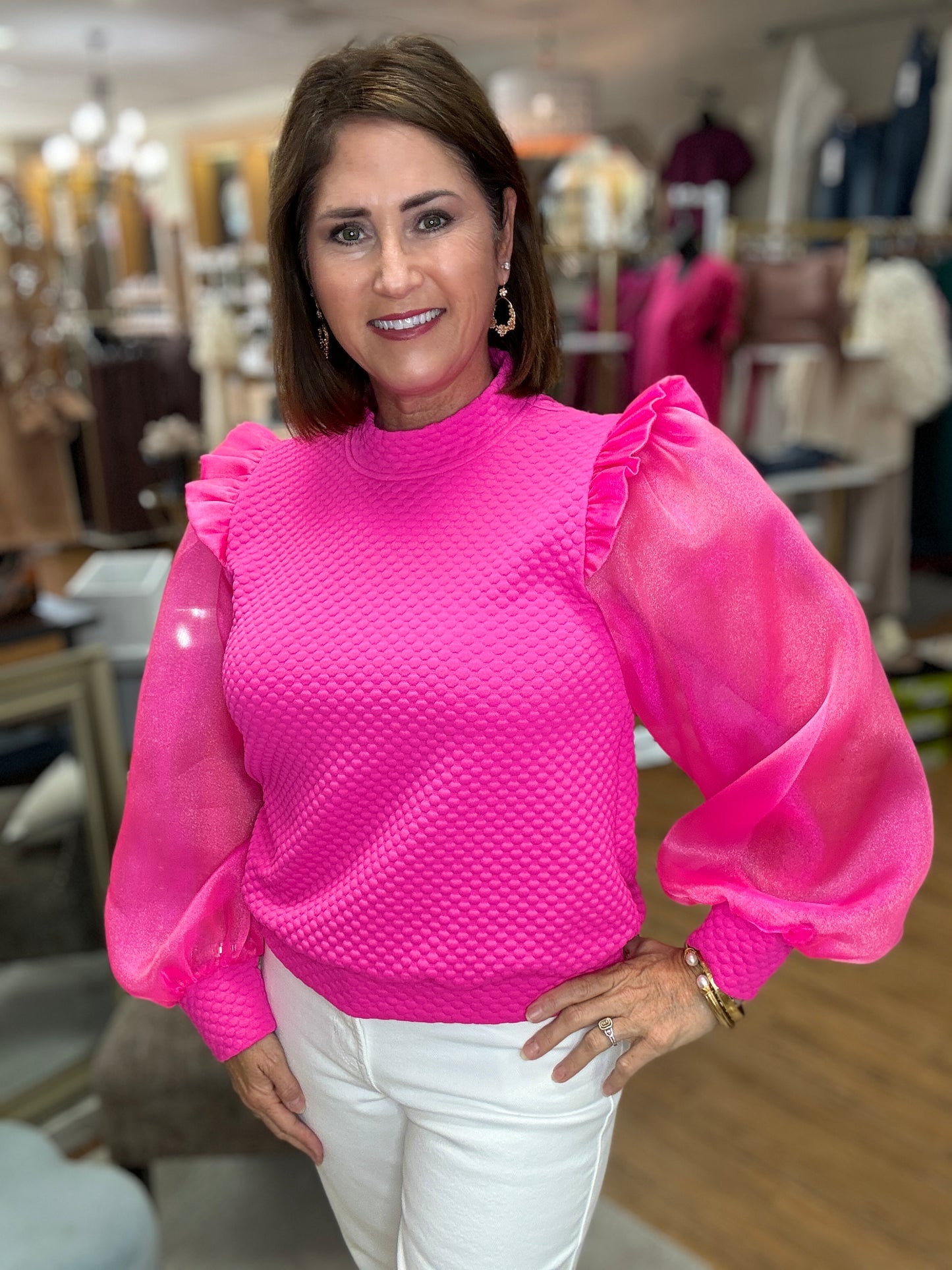 Mixed textured fabric feminine top with mock neck, back buttoned closure, frilled shoulders, long puffed sleeves, and ribbing at the sleeve ends and hemline.